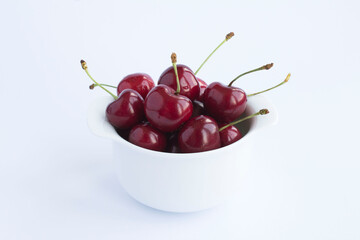 Red cherries in the white bowl on the white background. Closeup.