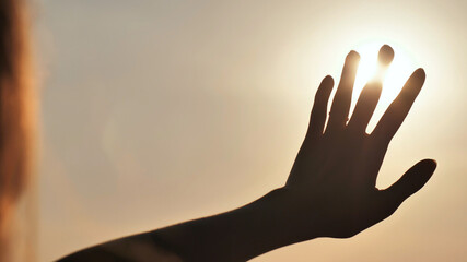 The girl touches the sunset sun the fingers. Romantic concept.