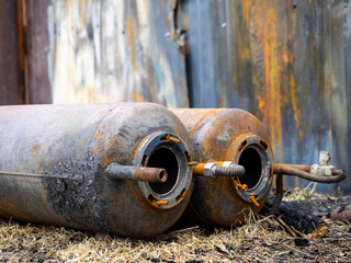 Old rusty gas cylinders lie on the ground, close-up. Dangerous cylinders as the cause of explosions and fires. Industrial background or screen saver. Corrosion and rust on metal