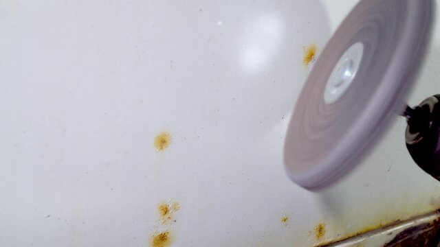 Mechanic grind paint from car body using drill with scotch brite circle