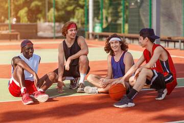 Joyful diverse basketball team taking break after their training at outdoor court