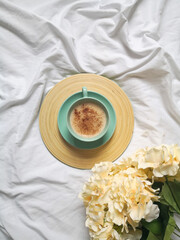 Creative flat lay composition with coffee and pampas grasshydrangea flowers on the bed. From above, top view, hygge concept.