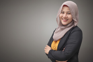 Asian muslim businesswoman wearing hijab smiling friendly with arms crossed, successful confident young woman