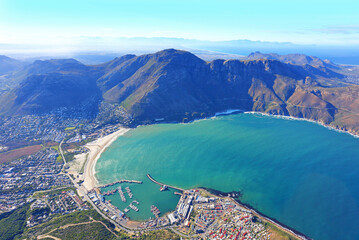 Cape Town, Western Cape / South Africa - 06/07/2019: Aerial photo of Hout Bay Harbour and Chapman's Peak, with Cape Flats in the background