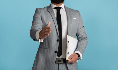 Close up view of businessman extending his hand for shake on blue background