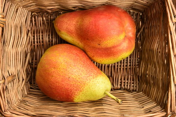 Organic juicy pears in a wicker basket, close-up.