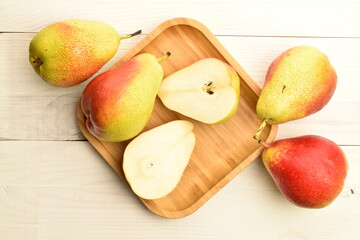 Sweet juicy pears with a bamboo plate on a white wooden table.
