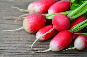 Bunch of fresh raw red radishes on old wooden background.Raphanus sativus.Healthy organic vegetable or vegan food concept.Selective focus.