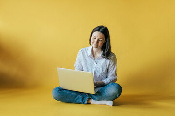 Young working woman on a laptop. The concept of remote work and independent freelance. 
Use of gadgets by the millennium generation.