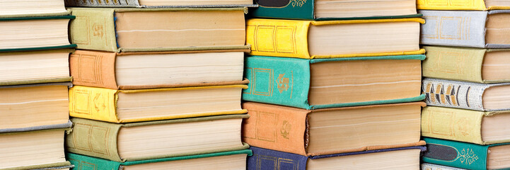 A stack of hardback books on a table in a library.