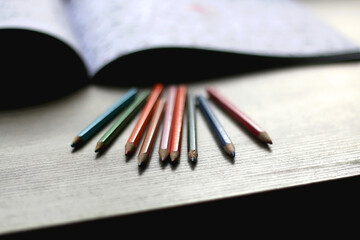 Coloring pencils and coloring book in the background. Selective focus.