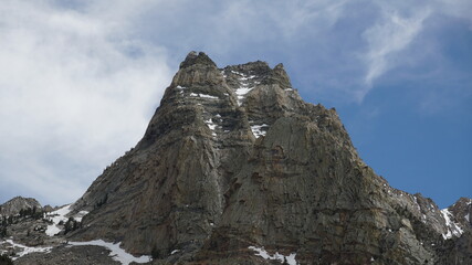 Mountain Peak Emerging From Long Winter with Like Layer of Snow and Blue Sky Background