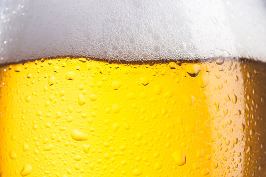 Close-up of cold beer glass with foam and drops. Selective focus.
