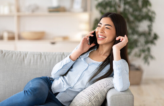 Phone Talk. Joyful Asian Girl Talking On Cellphone At Home