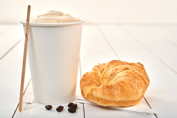 coffee cup and croissant isolated on a wooden table