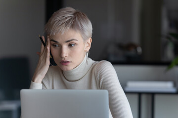 Serious short hired business woman sit in front of laptop considering decision she looking concerned. Thinking, deliberation process, employee searching solution having problem feels confused concept