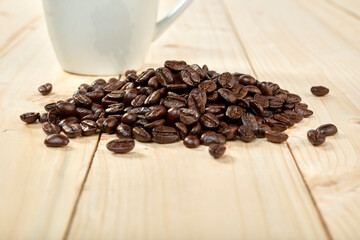 Coffee beans with coffee cup isolated on wooden table