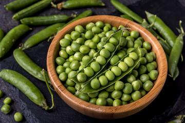 young  green peeled peas in a bowl on black background