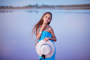 Fototapeta premium travels. beautiful girl on the lake. child on the beach. beautiful sunset. portrait of a child. long haired girl. relaxation and relaxation
