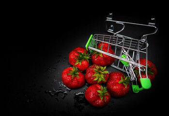 Strawberries in a supermarket cart are scattered on a black background
