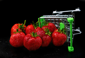 Strawberries in a supermarket cart are scattered on a black background