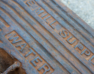 An old water meter lid with colorful orange rust and aqua patina found in an industrial dump.