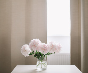 Beautiful pink peonies in a vase at home interior. Flower composition. Floral shop concept. Beautiful fresh cut bouquet. copyspace