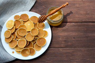 Cereal Pancakes. American gorgeous pancakes in a white plate and honey on an old wooden table. Tasty traditional american breakfast. View from above.