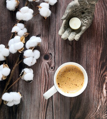 Composition with a coffee cup, a bouquet of cotton flowers and a candle in stone hand on a dark wooden table. Flat lay, from above, top view.