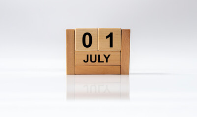july 1 1st first. Day 1 of month, handmade wood cube calendar on white glossy background with reflection. summer month, day of the year concept.