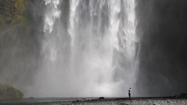 Man taking photos of Skogafoss waterfall Iceland slow motion close up