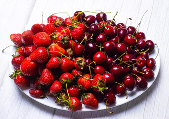 Ripe cherries and strawberries on a white dish