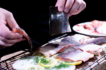 the cook puts pieces of delicious red fish on the grill with onions and lemon and herbs