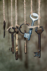 Old rusty keys hanged on the ropes with blurred grunge background