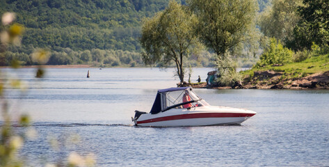 Fototapeta premium a boat with a motor floats along the river to the shore