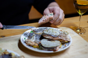 slices of red fish with lemon on a plate decorated with greens with a glass of white wine