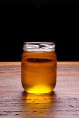 Glass jar with ghee and spoon with gold butter . Rustic still life over wooden background.