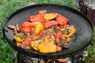 Fresh vegetables are cooked in a grill pan on open fire
