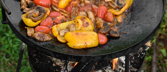 Fresh vegetables are cooked in a grill pan on open fire