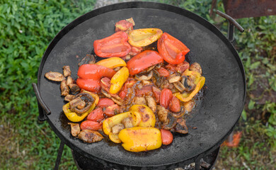Fresh vegetables are cooked in a grill pan on open fire
