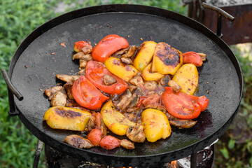 Fresh vegetables are cooked in a grill pan on open fire