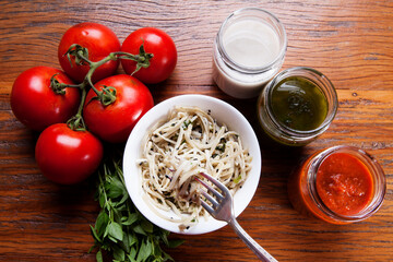 Nutrition concept - Healthy food, Diet, Detox, Clean Eating or Vegetarian concept. Healthy pasta with sauce, basil, fresh tomatoes over rustic wooden background