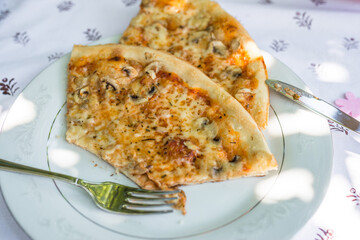 Pieces of pizza on a plate on a table with tablecloth and cutlery, Germany