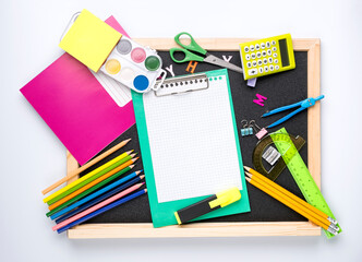 Many different school supplies on blackboard copy space background. Back to school concept.