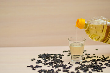 Pour vegetable oil from a plastic bottle into an insulated glass. Sunflower oil. Sunflower seed.