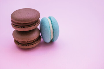 Macarons macaroni cookies. Biscuits, chocolate and turquoise colors. Cake with cream filling on a pink background.