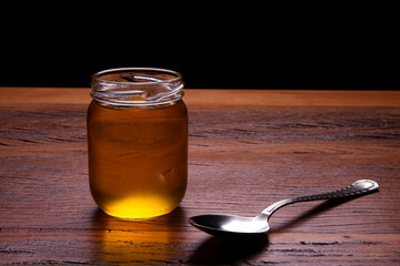 Glass jar with ghee and gold butter. Rustic still life food jar over wooden background.