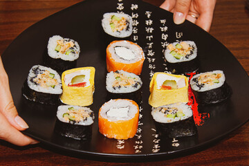 Different sushi rolls on the table in plates with sauces.