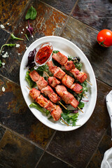 Pork skewers with sauce and herbs on a wooden skewer