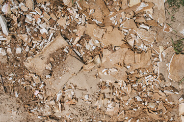 The texture of broken tiles, stones on the sandy brown ground. Top view of the devastation. Photography, concept.